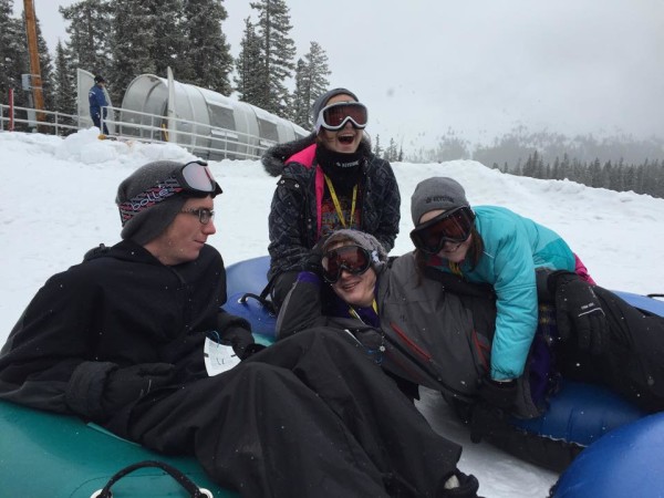 A family enjoys tubing in the snow.